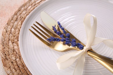 Photo of Cutlery, plate and preserved lavender flowers on color textured table, closeup