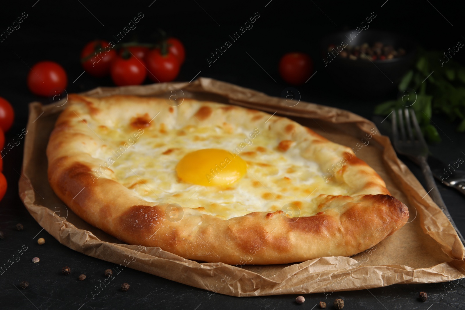 Photo of Fresh delicious Adjarian khachapuri served on black table