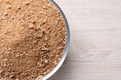 Fresh breadcrumbs in bowl on white wooden table, top view. Space for text