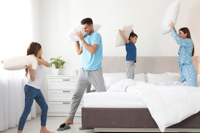 Photo of Happy family having pillow fight in bedroom