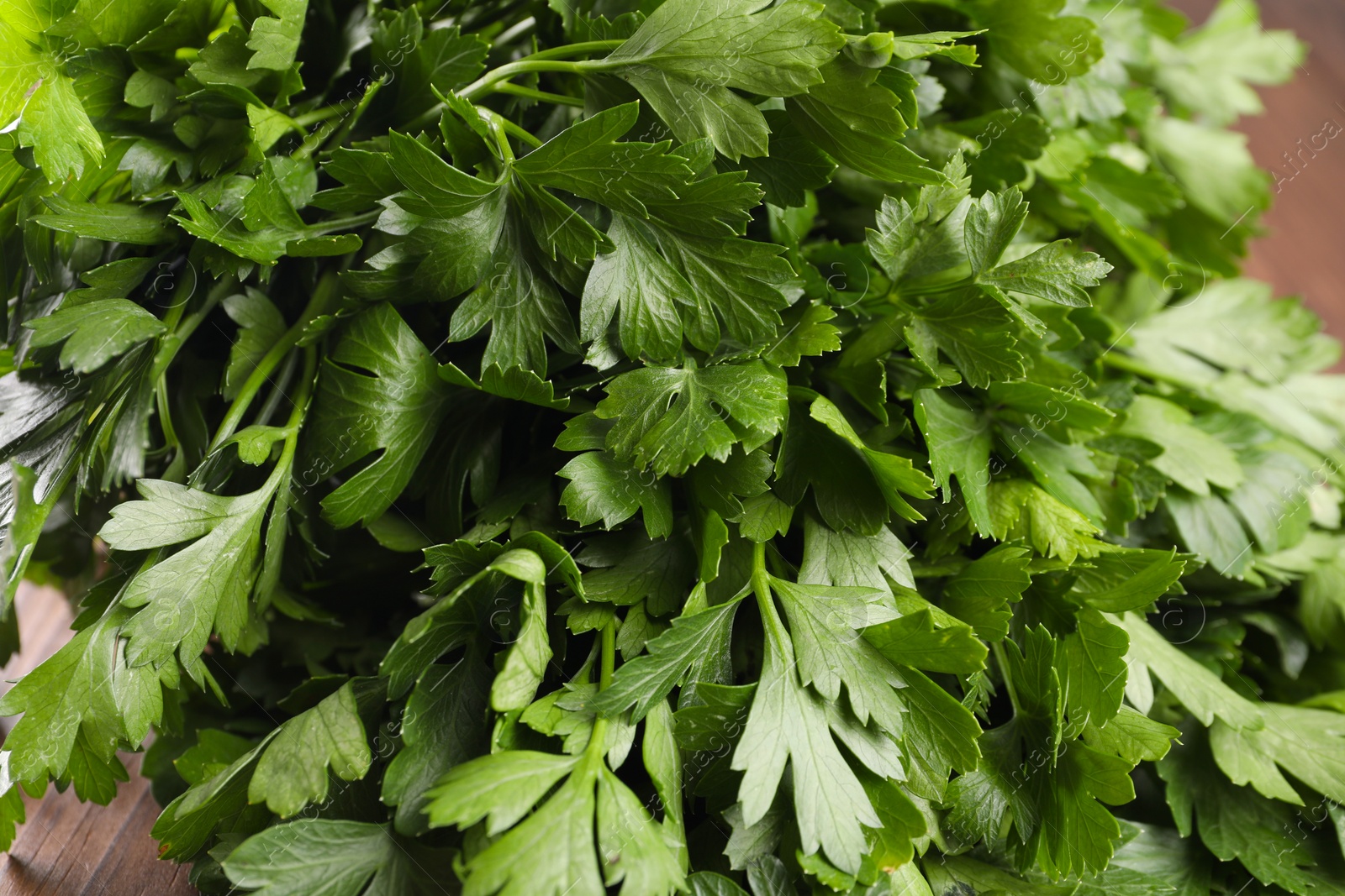 Photo of Fresh green parsley leaves on wooden table, closeup