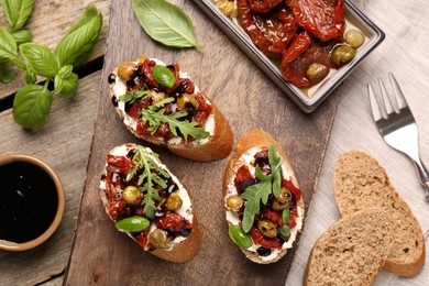 Delicious bruschettas with balsamic vinegar and toppings served on wooden table, flat lay