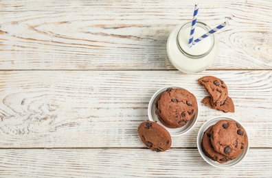 Flat lay composition with tasty chocolate chip cookies on wooden background. Space for text