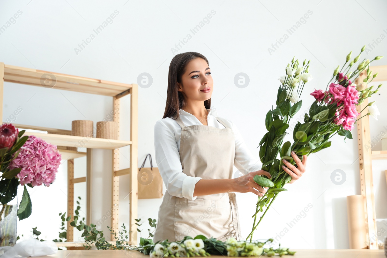 Photo of Florist making beautiful bouquet at table in workshop