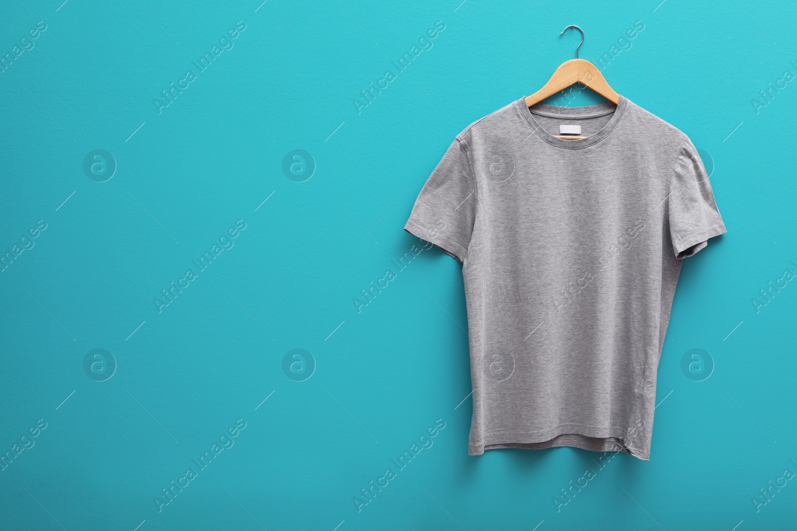 Photo of Hanger with blank t-shirt on color background. Mockup for design