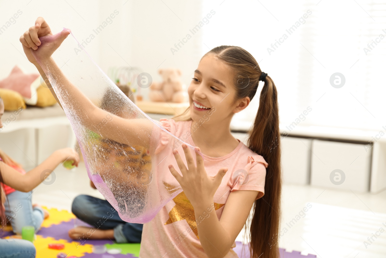 Photo of Preteen girl playing with slime in room