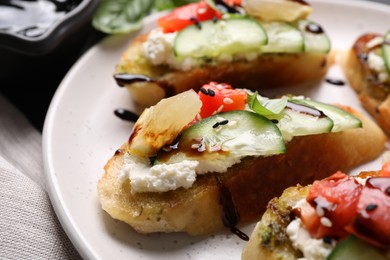 Photo of Delicious bruschettas with balsamic vinegar and toppings on plate, closeup
