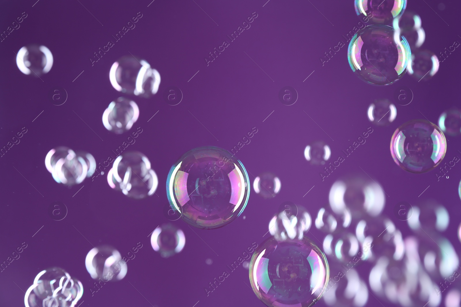 Photo of Beautiful transparent soap bubbles on purple background