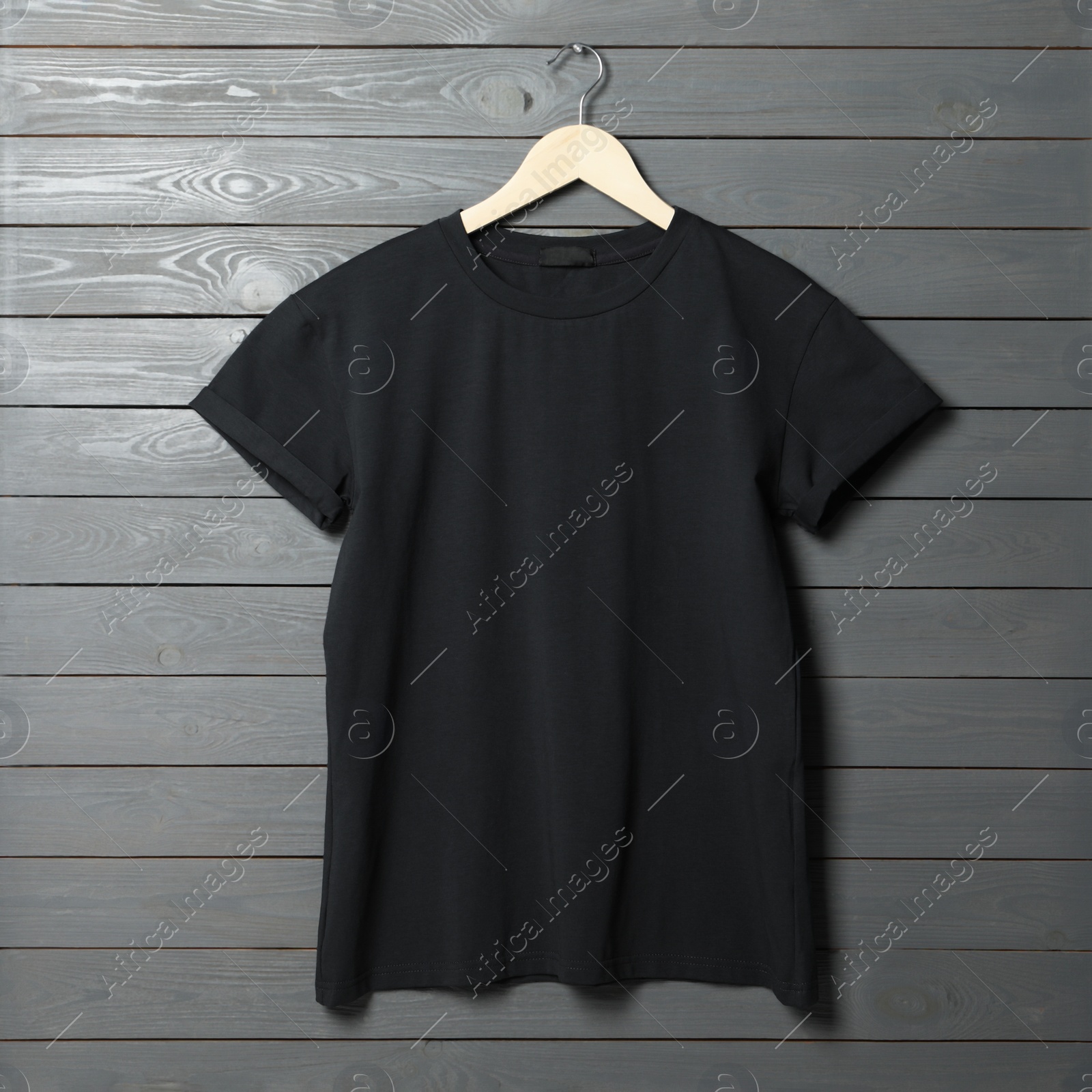 Photo of Hanger with stylish black T-shirt on gray wooden wall