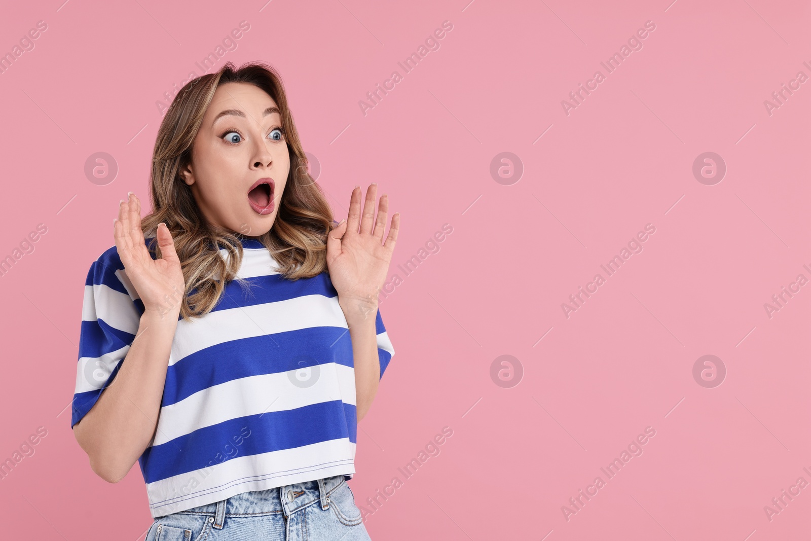 Photo of Portrait of surprised woman on pink background. Space for text