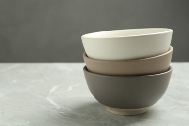 Stylish empty ceramic bowls on grey table, space for text. Cooking utensils