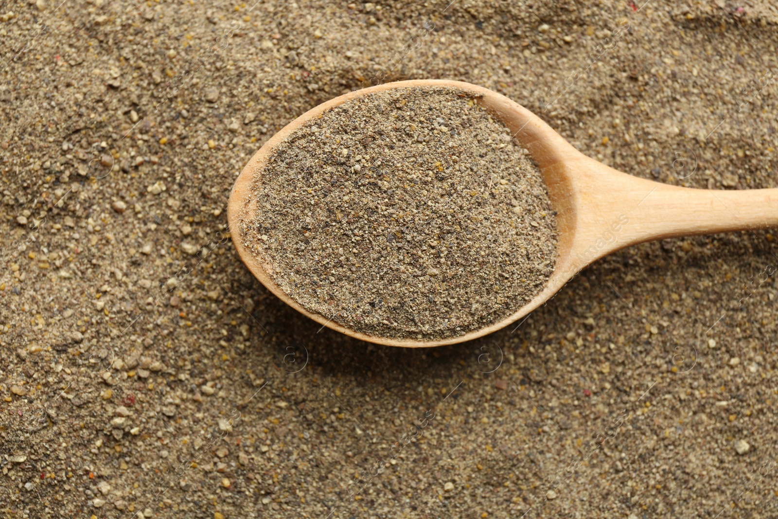 Photo of Closeup of wooden spoon with ground black pepper, top view
