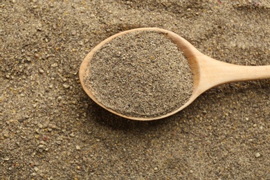 Closeup of wooden spoon with ground black pepper, top view