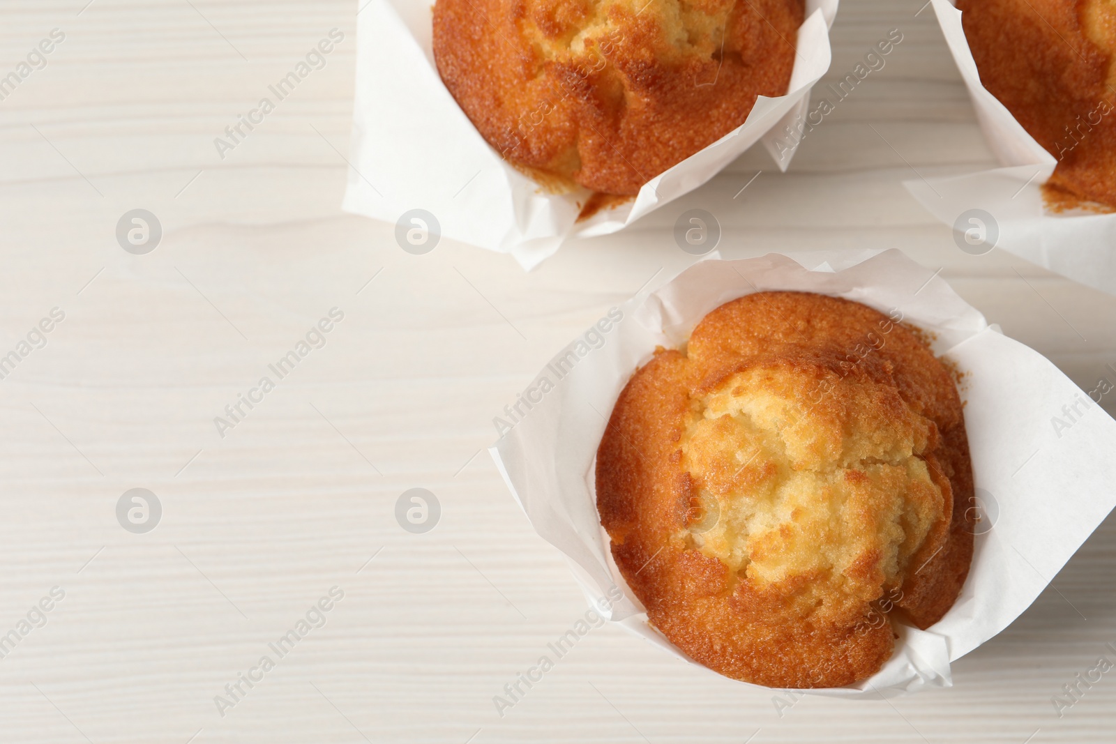Photo of Tasty muffins on white wooden table, flat lay. Space for text