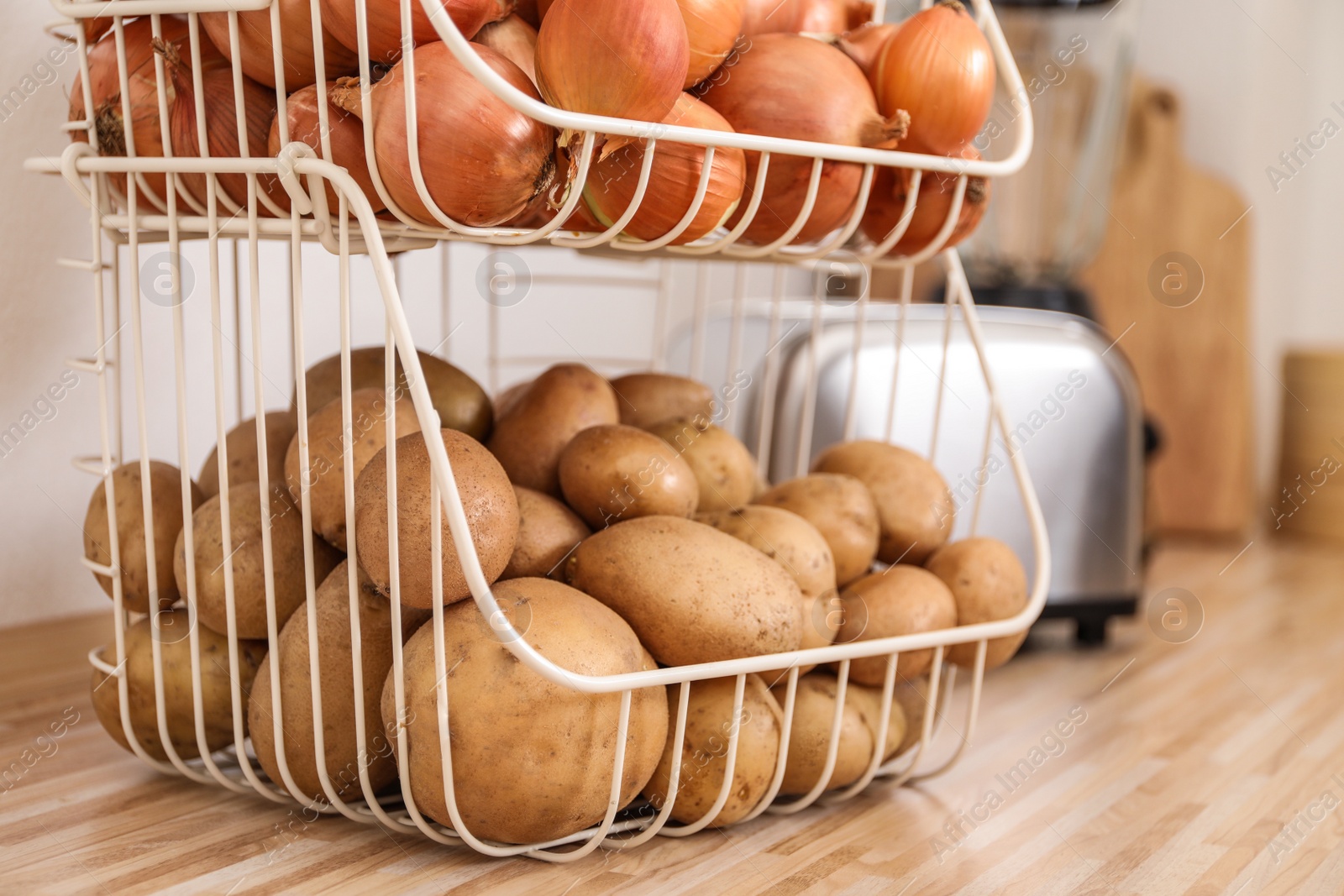 Photo of Container with potatoes and onions on wooden kitchen counter. Orderly storage