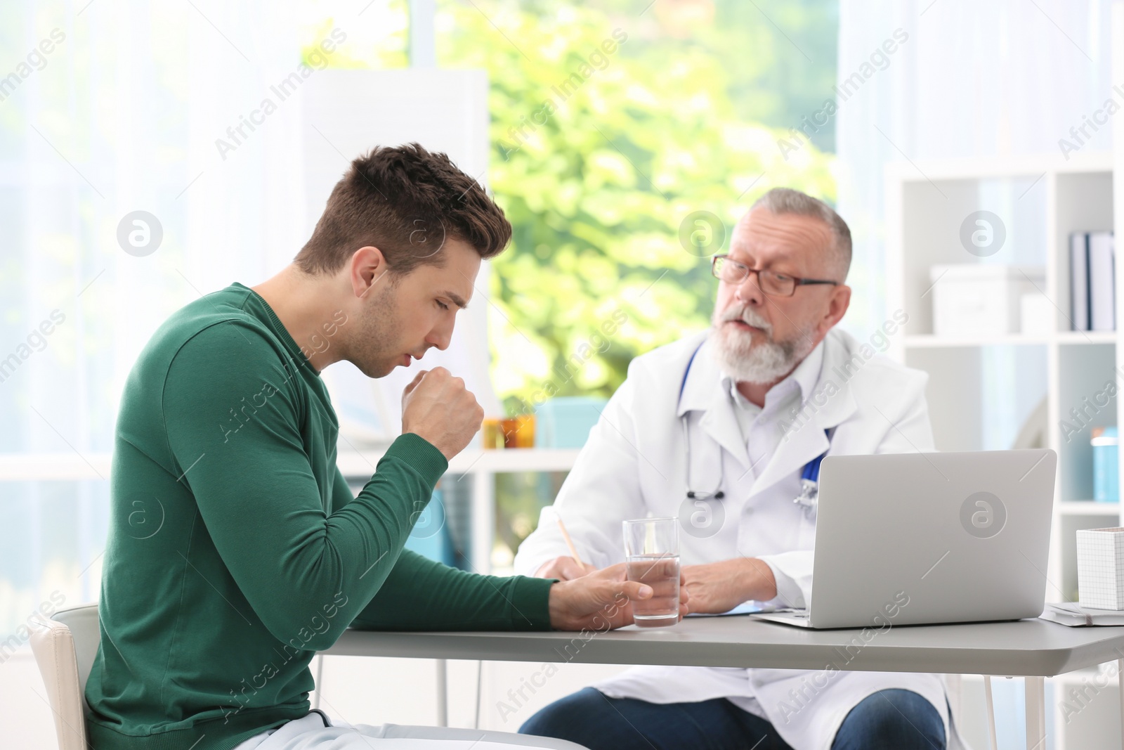 Photo of Coughing young man visiting doctor at clinic