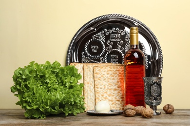 Photo of Symbolic Passover (Pesach) items on wooden table against color background