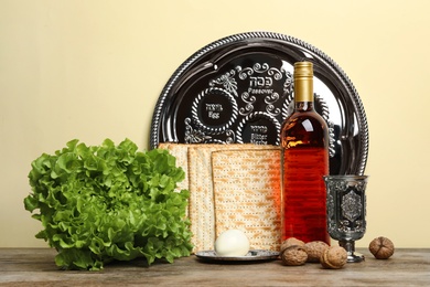 Symbolic Passover (Pesach) items on wooden table against color background