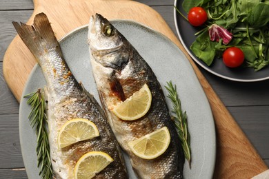 Photo of Delicious baked fish served on grey wooden table, top view