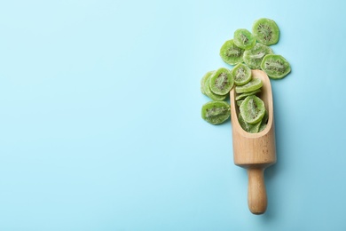 Scoop of dried kiwi on color background, top view with space for text. Tasty and healthy fruit