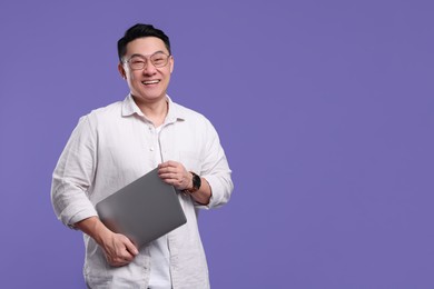 Photo of Happy man with laptop on lilac background, space for text