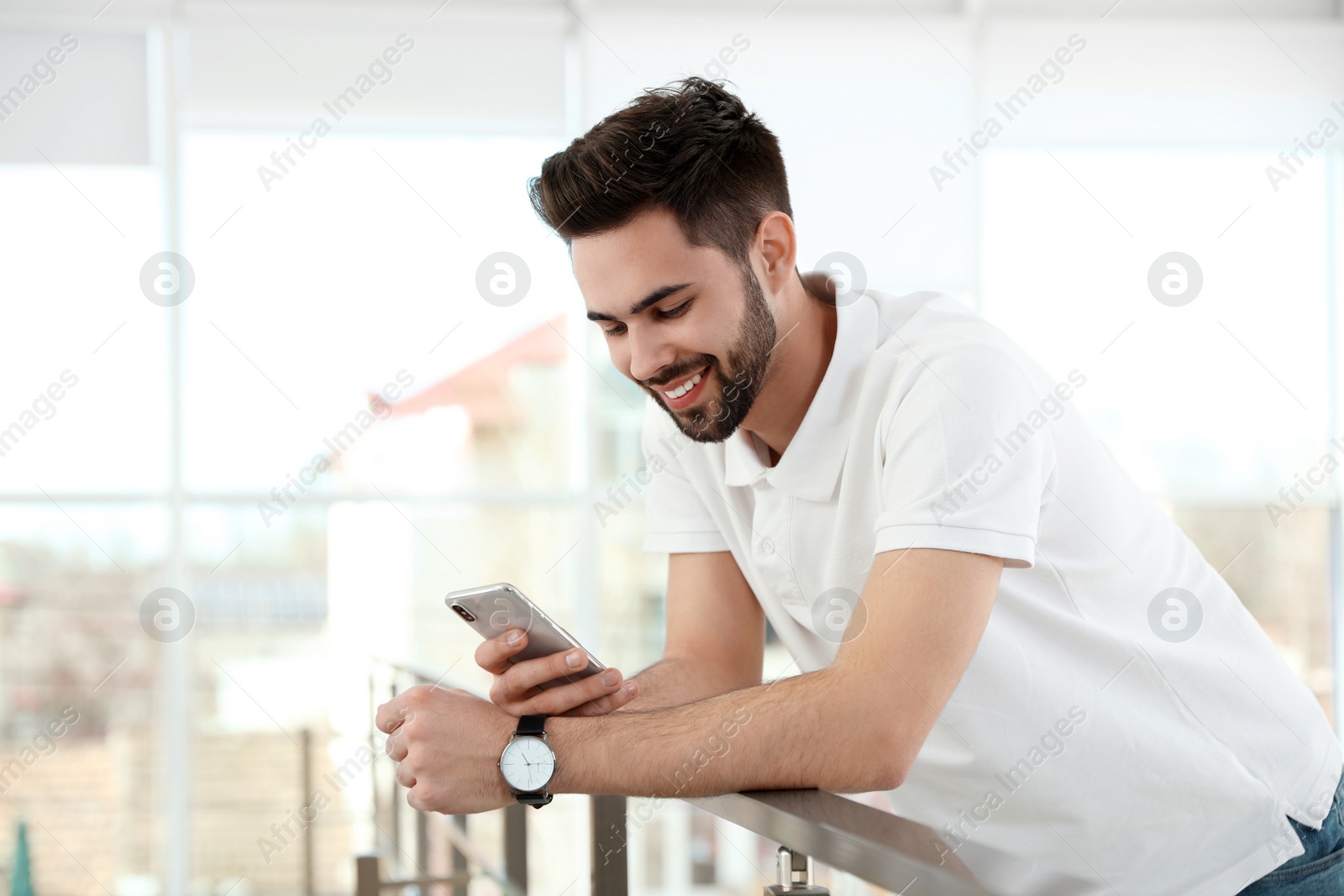 Photo of Portrait of handsome man with mobile phone in light room