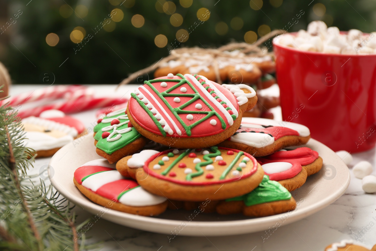 Photo of Decorated cookies and hot drink on white marble table against blurred Christmas lights, closeup