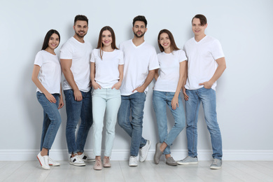Group of young people in stylish jeans near light wall