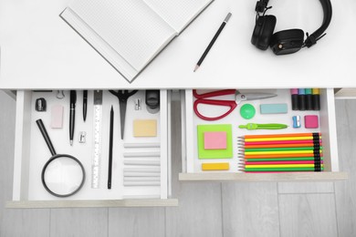 Photo of Office supplies in open desk drawers, top view