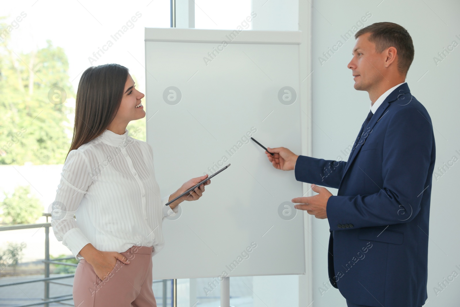 Photo of Office employees talking near whiteboard at workplace