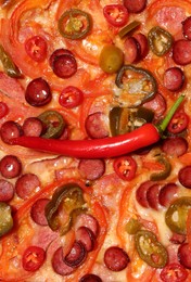 Delicious pizza Diablo with chili pepper as background, top view