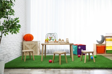 Stylish playroom interior with toys and modern wooden furniture