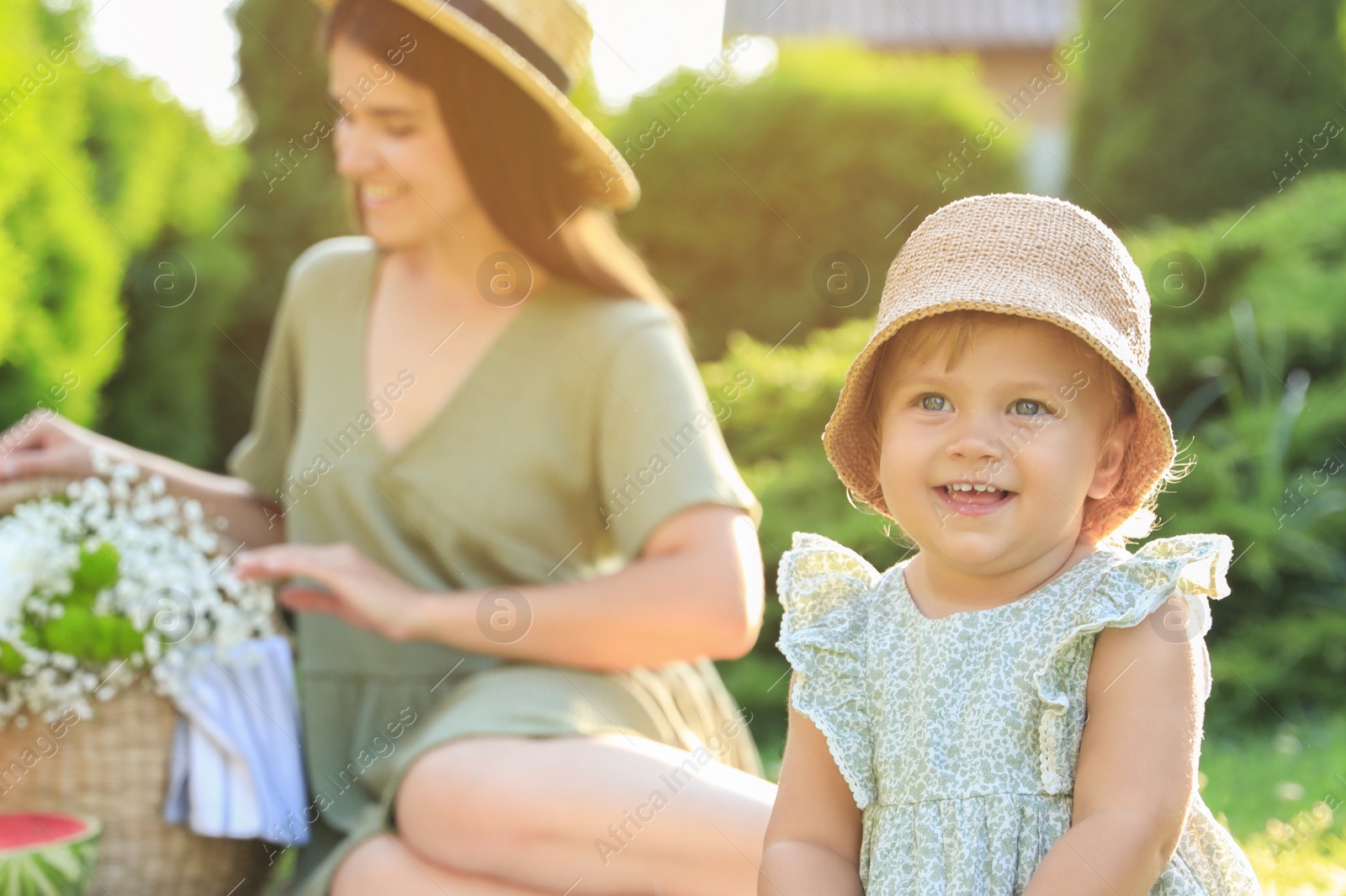 Photo of Mother and her daughter having picnic in garden, focus on baby