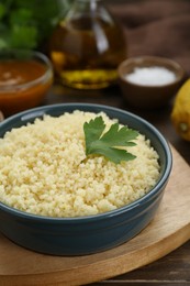 Photo of Tasty couscous with parsley on wooden table, closeup