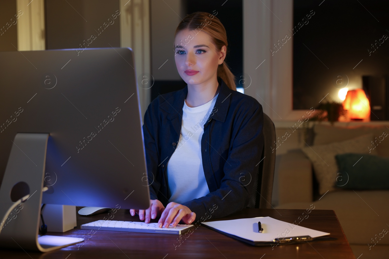 Photo of Home workplace. Woman working on computer at wooden desk in room