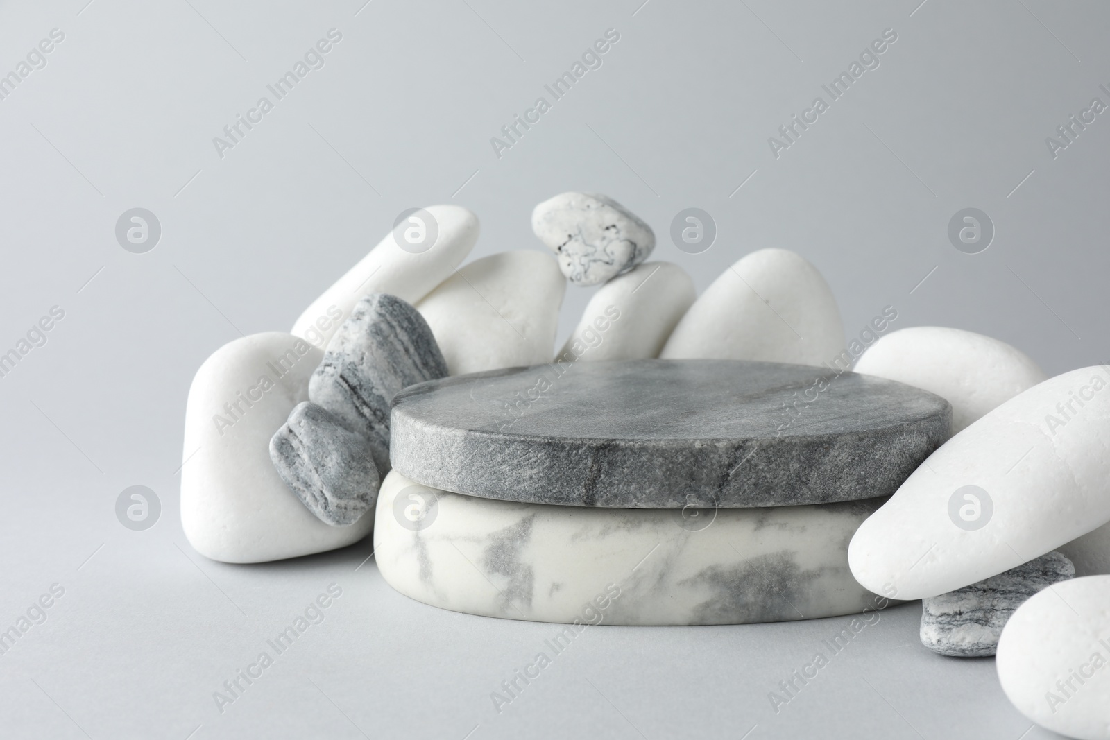 Photo of Presentation for product. Stone podium and pebbles on light grey background.