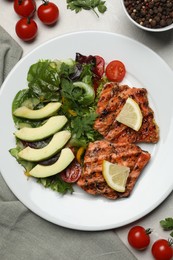 Tasty grilled salmon with avocado, lemon and tomatoes on light grey table, flat lay