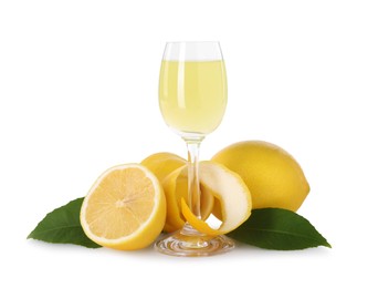 Photo of Liqueur glass with tasty limoncello, lemons and green leaves isolated on white