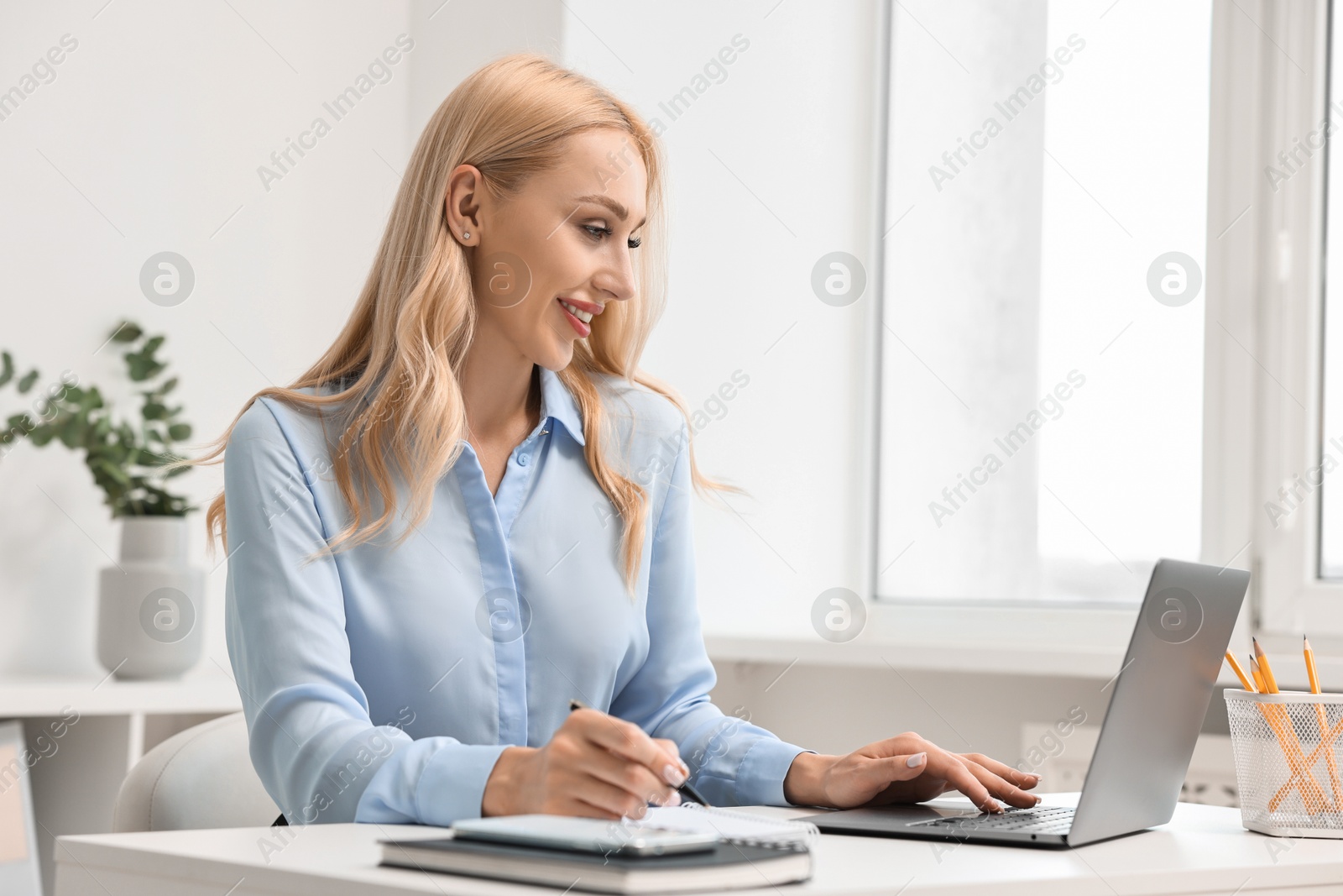 Photo of Happy secretary working with laptop in office