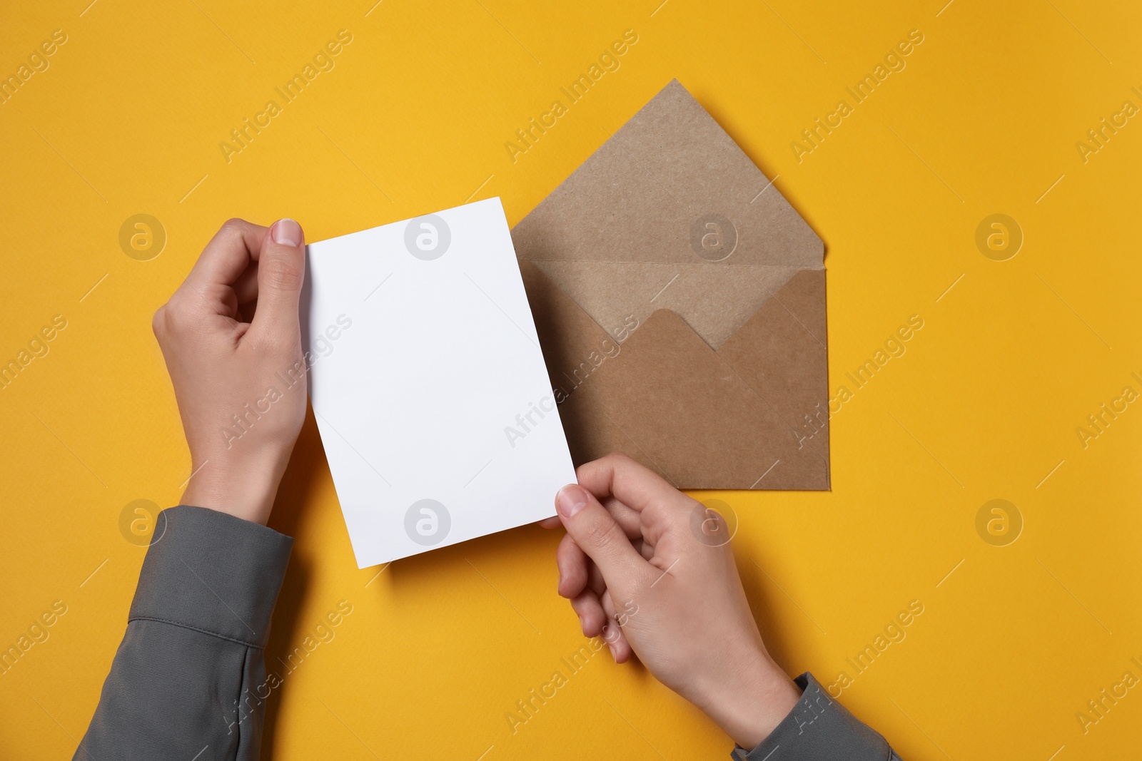 Photo of Woman with blank card at orange table, top view. Space for text