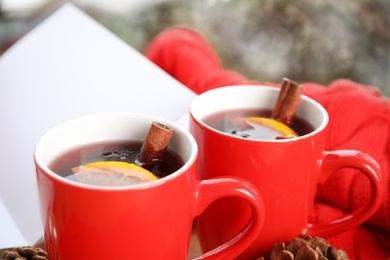 Photo of Cups of hot winter drink on blurred background, closeup