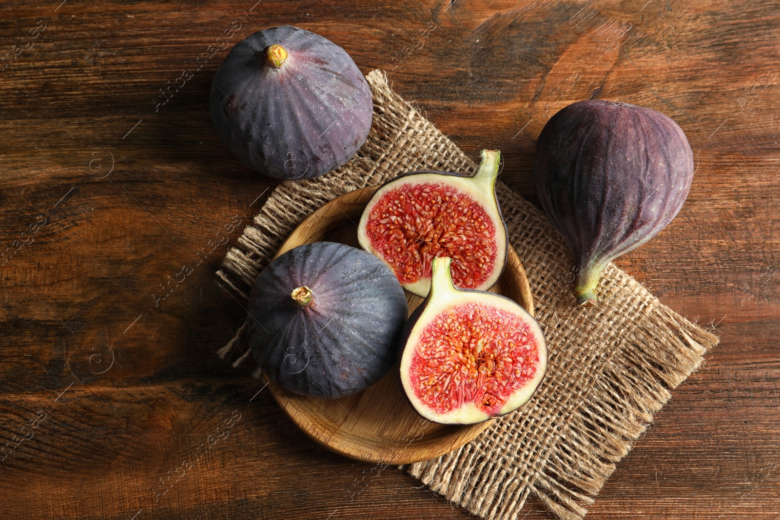 Photo of Plate with fresh ripe figs on wooden background, top view