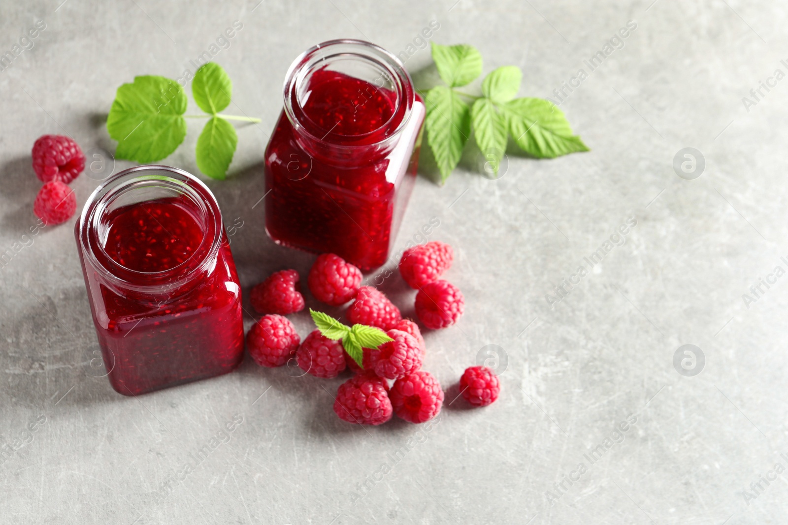 Image of Sweet raspberry jam and fresh berries on table, space for text