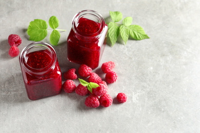 Image of Sweet raspberry jam and fresh berries on table, space for text