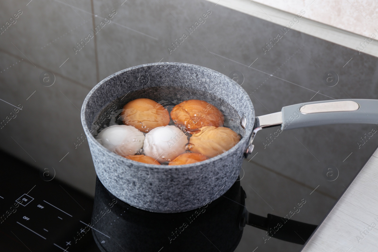 Photo of Chicken eggs boiling in saucepan on electric stove