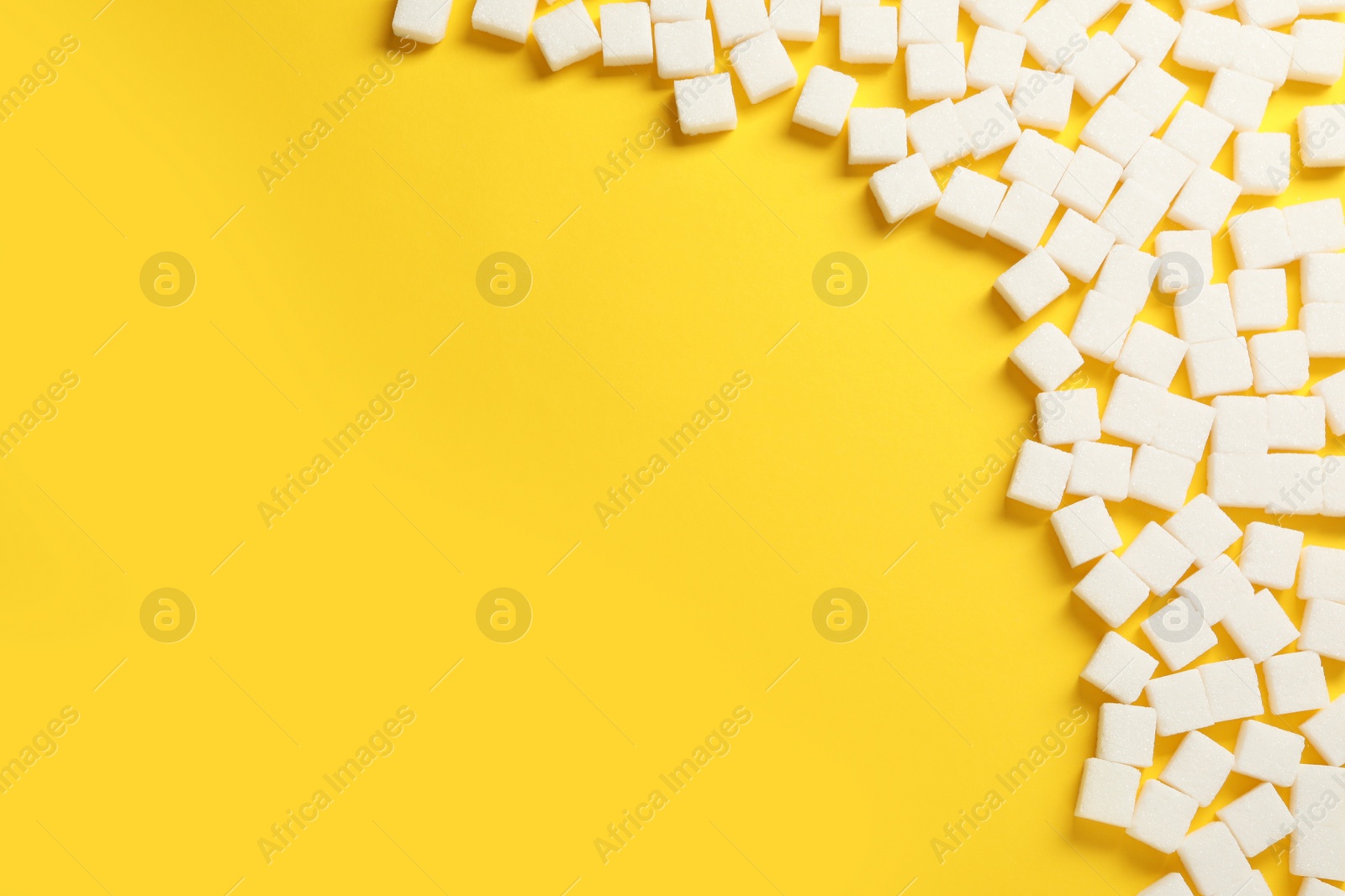 Photo of White sugar cubes on yellow background, flat lay. Space for text