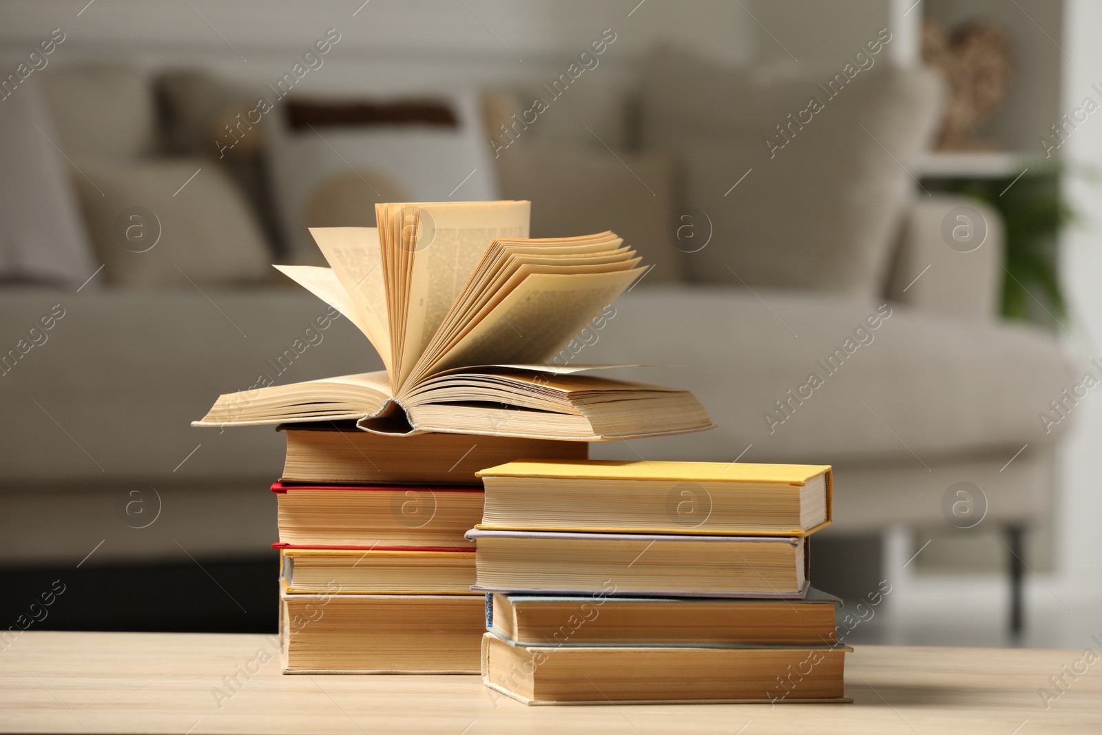 Photo of Many books on wooden table in living room. Home library