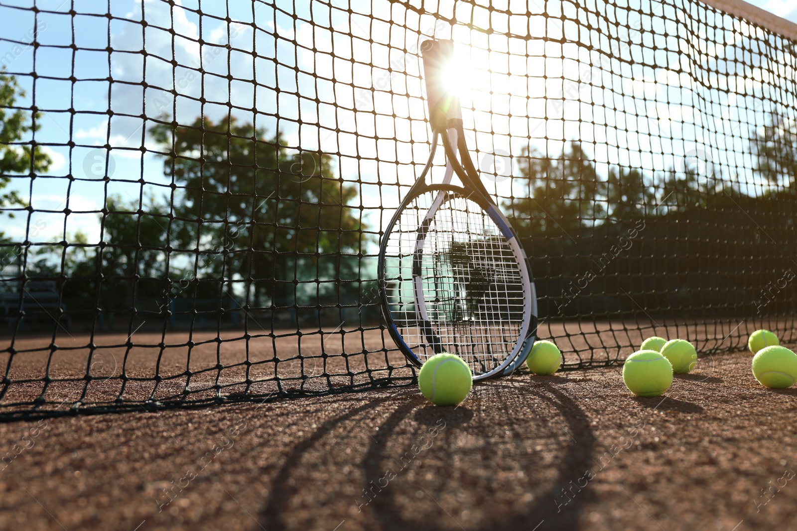 Photo of Tennis balls and rackets near net on clay court