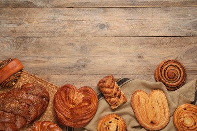 Photo of Different tasty freshly baked pastries on wooden table, flat lay. Space for text