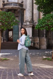 Photo of Travel blogger with backpack recording video on city street